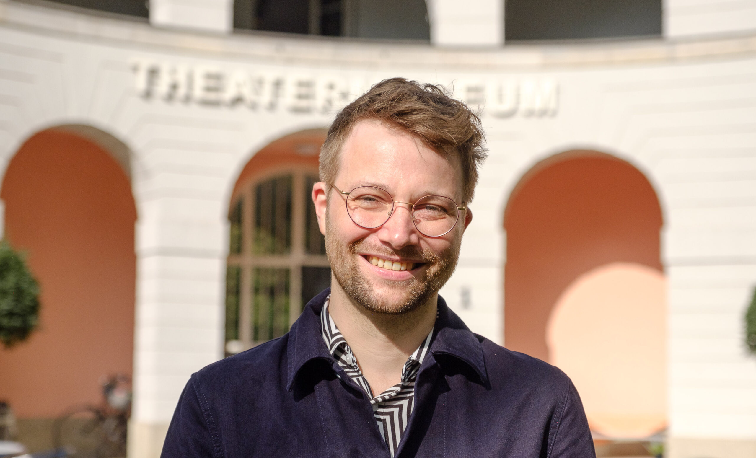 Sascha Förster steht freundlich lächelnd vor dem Theaterrmuseum in Düsseldorf